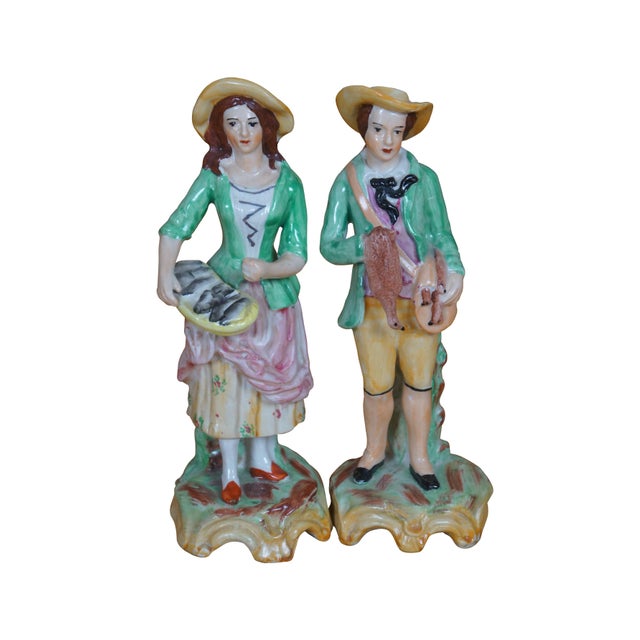 Old Staffordshire Ware England porcelain figurines depicting a pair of figures in green, pink, and yellow, carrying a...
