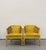 A distinctive pair of vintage barrel-back armchairs featuring warm cream-painted wood frames, woven cane side panels, and...