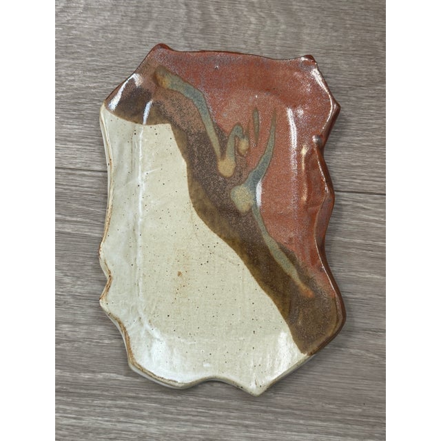 A unique handmade studio pottery spoon rest featuring an abstract swirl of warm browns, creams, and earthy neutrals. The...
