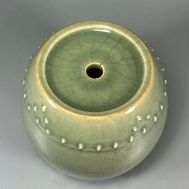 This vintage‑style rounded celadon jar adopts delicate crackled green glaze, decorated with rows of raised dot ornaments...
