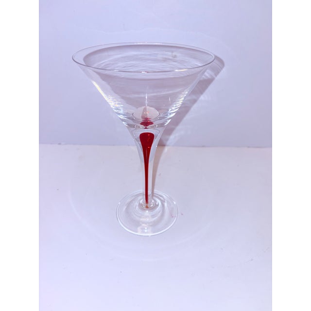 A striking set of four sculptural martini glasses featuring crystal-clear bowls balanced on elegant stems infused with a...