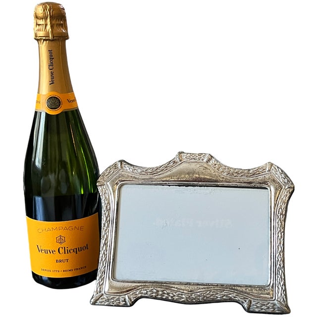 A romantic silverplated picture frame featuring a sculpted leafy border, gently curved sides, and distinctive peaked...