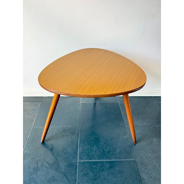 This large triangular coffee / side table features a mid-century modern design with a formica-covered top and tapered...