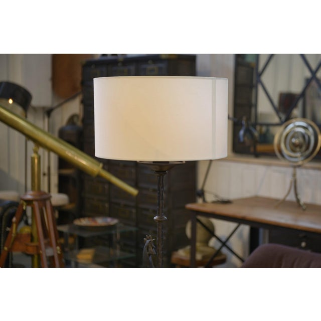 Wrought iron floor lamp in the style of the Marolles workshops, 1950s. Slender, hammered stem with a striking graphic...