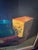 A handsome large-scale vintage still life painting featuring a richly layered arrangement of antique books, fruit,...