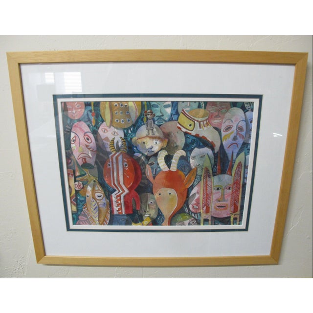 Framed watercolor painting featuring an assemblage of colorful, stylized tribal, ceremonial, and everyday masks with...