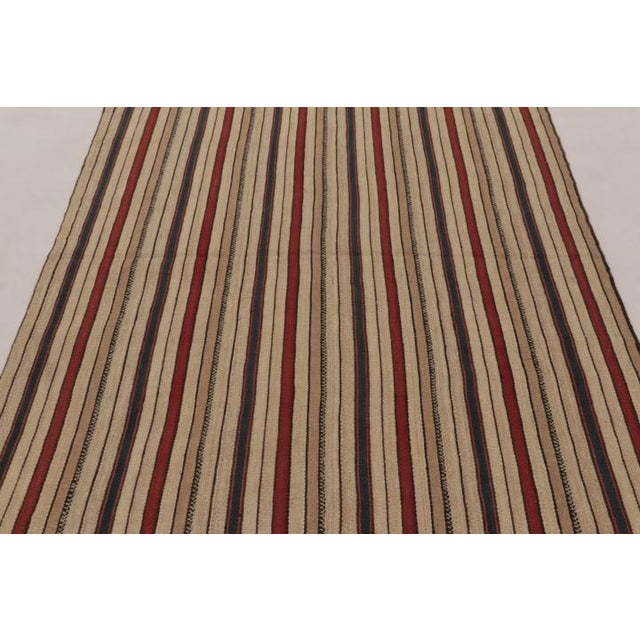 Handwoven in wool and originating circa 1950-1960, this 5x7 vintage Persian kilim is a rich new tribal addition to the Rug...