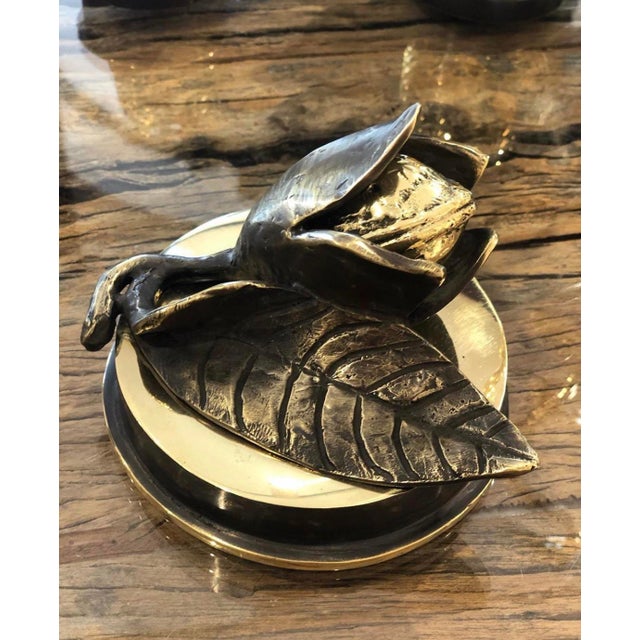 A contemporary still-life bronze of an opening nut, its halves parting to reveal the kernel within, set above a single...