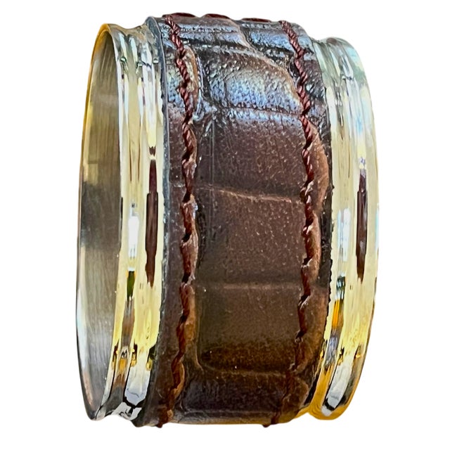 A handsome set of eight napkin rings combining rich chocolate-brown crocodile-pattern bands with polished silver-tone...