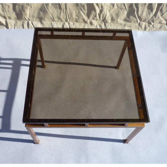 Small side table with a smoked bronze glass top on a square steel tube frame with a "bronze-copper" finish. Two are...