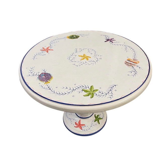 A charming vintage-inspired Italian ceramic bistro table featuring a vibrant, hand-painted aquatic motif. This pedestal-...