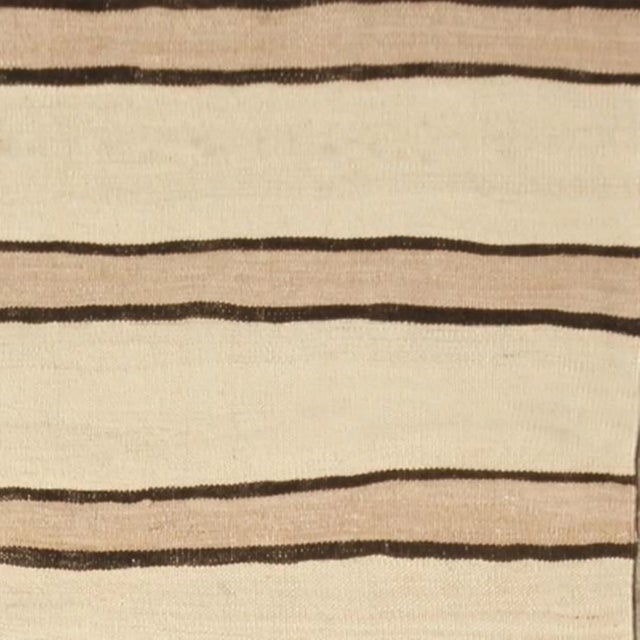 Handwoven in a wool flatweave originating from Turkey circa 1950-1960, this vintage Kilim rug connotes a mid-century...