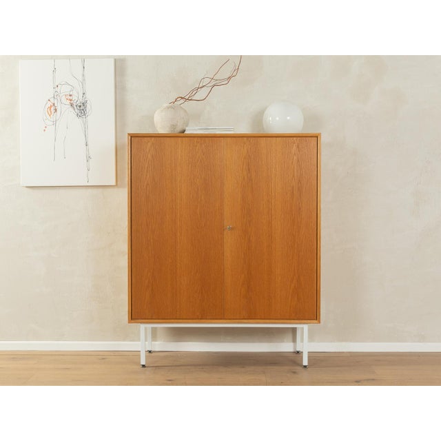 Classic chest of drawers from the 1960s. Body in oak veneer with two cabinet doors, three shelves and new square steel...