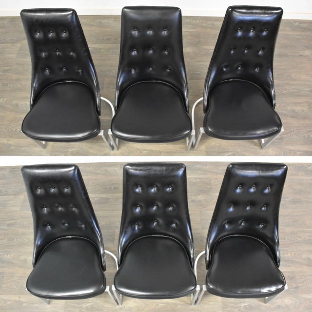 A set of six mid century modern aluminum base dining chairs in a black vinyl. Minor wear and tears shown. Seat height is...