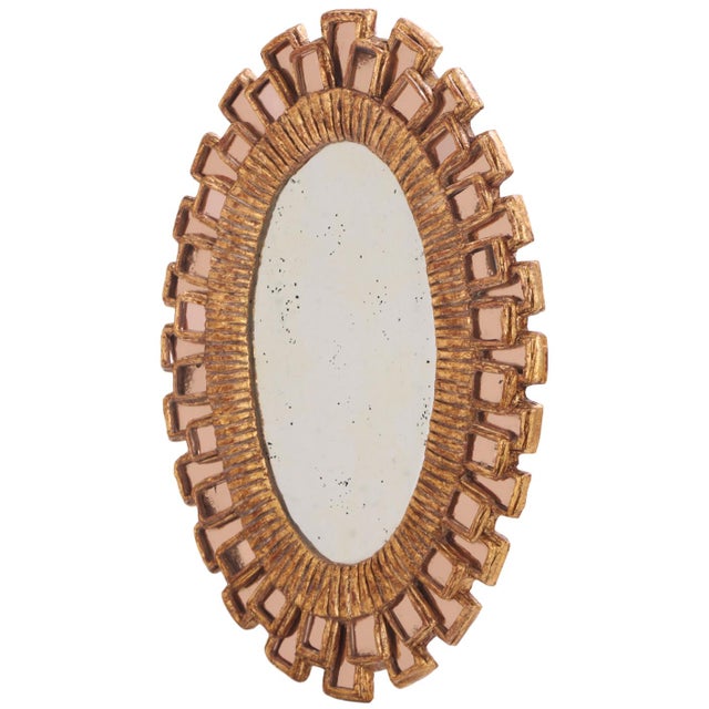 An elegant oval mirror featuring a sculptural gilt resin frame accented with pink glass elements, inspired by the...