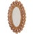 An elegant oval mirror featuring a sculptural gilt resin frame accented with pink glass elements, inspired by the...