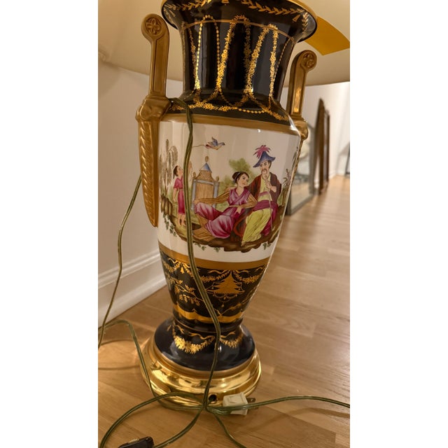 Pair of vintage hand-painted porcelain urn table lamps in a classic Chinoiserie style. Black lacquered body with gold...