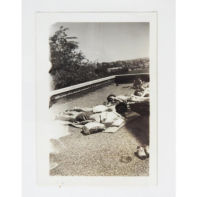 Mid 20th century vernacular snapshot photograph of a group of women sunbathing backless on a rooftop. Unframed.