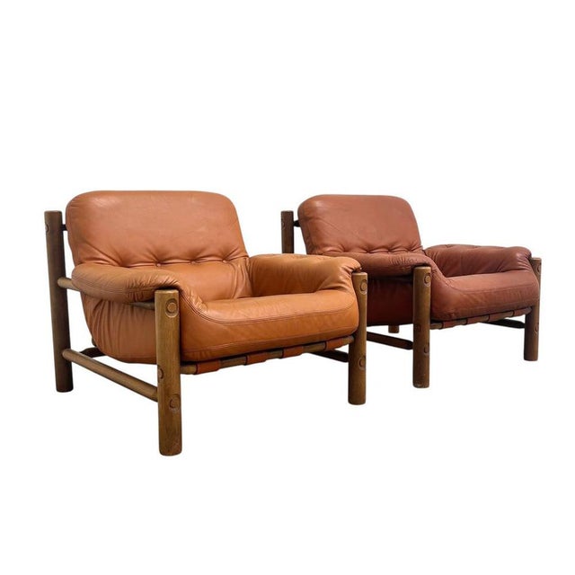 Remarks: Set mid century brutalist lounge chairs in Brazilian style, 1960s. Oak frame with cognac leather upholstery. Both...