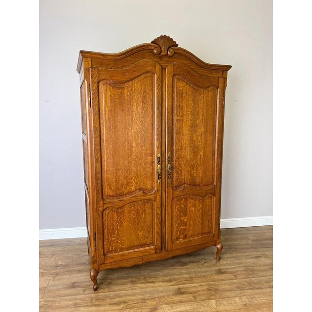 A beautifully presented Vintage French Louis wardrobe in oak, featuring two shaped panelled doors, a decorative curved top...