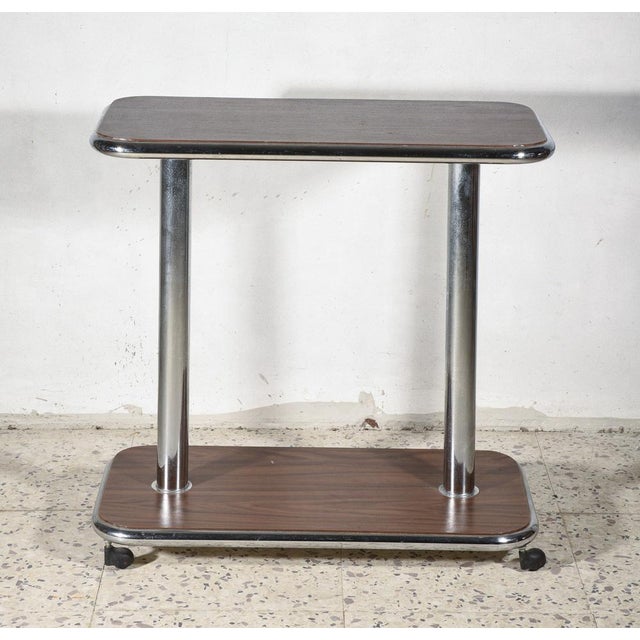 A small table on wheels that doubles as a trolley, featuring a double shelf made of compressed veneered wood with a...