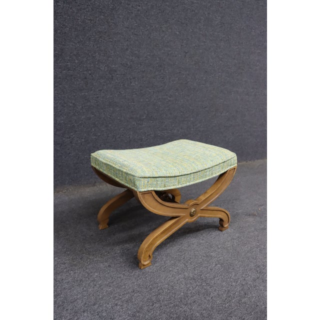 Cherry wood bench with an X-form base, carved center medallions, and an upholstered seat. Finished in a warm cherry tone...