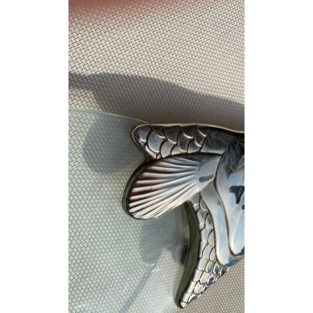 This trivet is a centerpiece in metal and glass. It has been made in France, around 1970. The pattern is a silver fish shape.