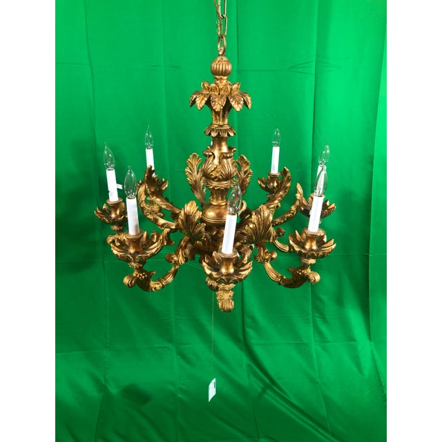 Hand carved eight light chandelier featuring a acanthus leaf design in a slightly distressed gold gilt finish. Italy