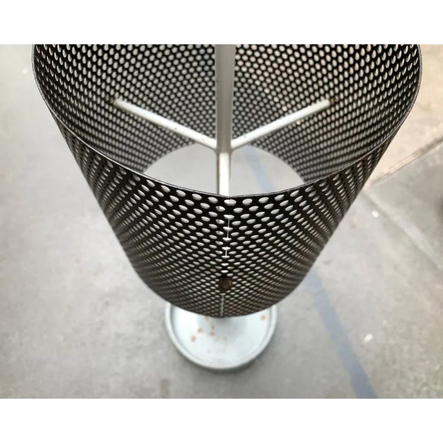 Minimalist Mid-Century shield stand made of perforated sheet. The perforated ring for recording the umbrellas hovers as a...