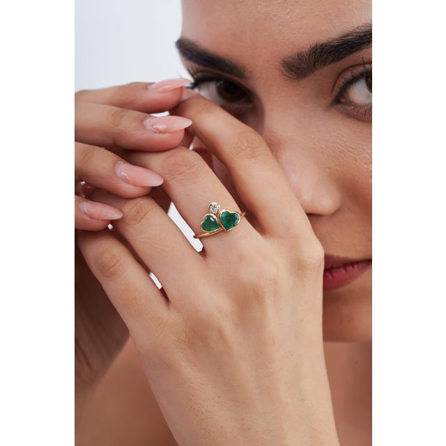 This heart cluster ring features 1.34 carats of vibrant green heart-cut emeralds, set in 14K yellow gold. The twin center...