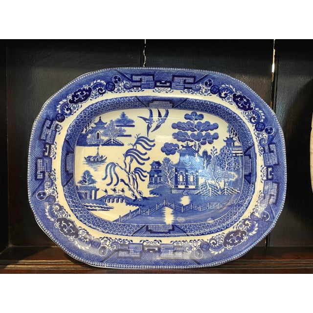 A rare collection of three 19th-century English Blue Willow ironstone serving platters featuring the iconic chinoiserie...
