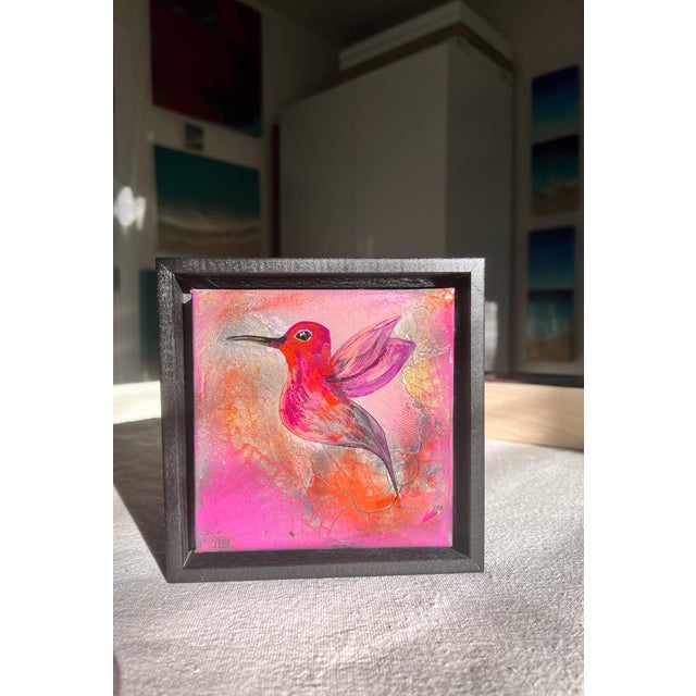This artwork features a vibrant hummingbird in mid-flight, captured in a dynamic pose against a textured background of...
