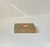 A brass cigarette or cigar box executed entirely of brass and set with an unusual and vivid circular enamel plaque in red...