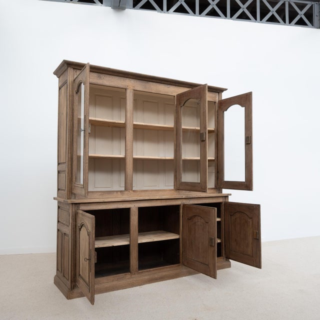 Antique 20th-century oak bookcase The upper section features three glass doors, adorned with molded frames and arched...