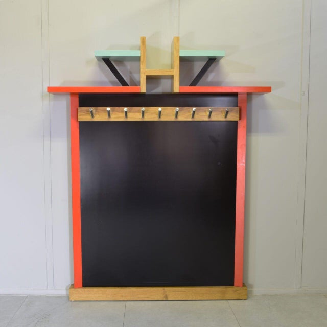 The piece is constructed from natural wood — likely ash — combined with black laminate panels and lacquered wood elements...