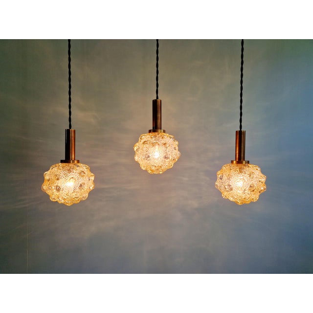 Set of three amber bubble glass pendant lights with brass mounts, designed by helena tynell for the german manufacturer...