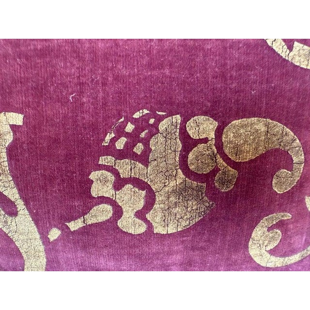 This stenciled velvet pillow by Nomi Textiles is a striking decorative piece, showcasing a luxurious eggplant base with an...