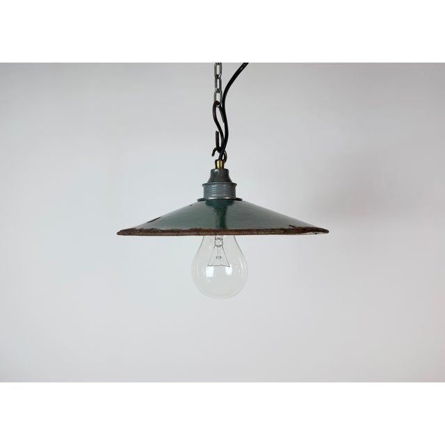 Vintage industrial enamel pendant lamp from the 1950s. It features a green enamel shade with white enamel interior and a...