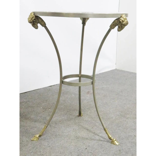 Jansen style gueridon table, steel frame with brass rams heads and hoof feet, white marble top. Made in the mid 20th century.