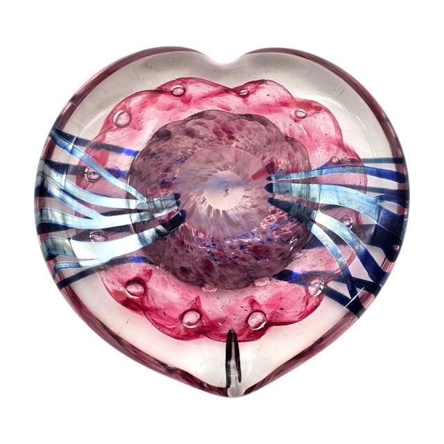 This hand-blown art glass heart paperweight presents a sculptural interpretation of the heart form, executed in layered...