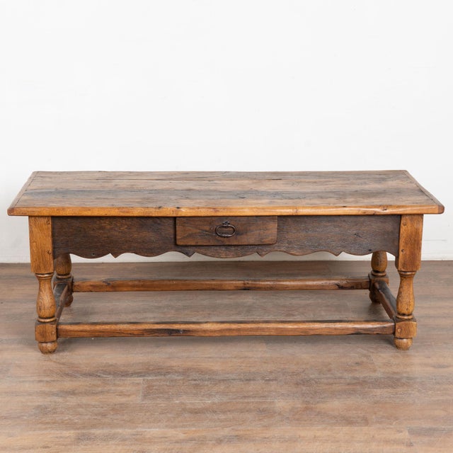20th century French coffee table, crafted in oak. The table features a carved scalloped skirt, one drawer with an iron...