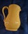 This hand-crafted Italian ceramic pitcher features a classic bulbous silhouette with a vibrant ochre yellow glaze and a...