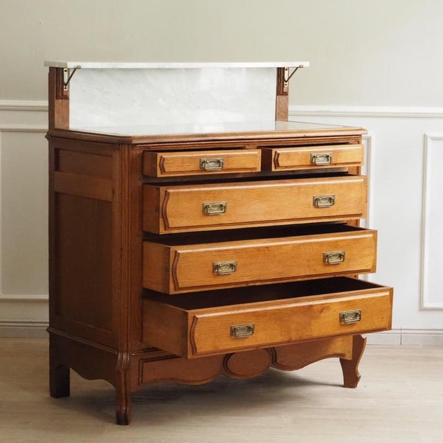 This antique oak vanity with white marble and a curved mirror top dates from around 1910 and features an elegantly...