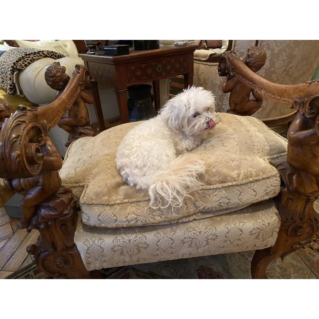 An Italian Baroque style carved bench in the manner of Andrea Brustolon. The carved armrests each supported by figural...