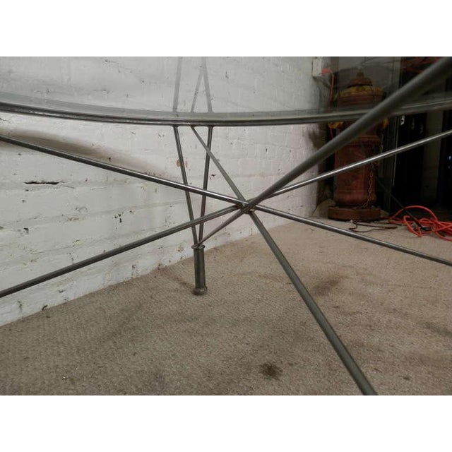 Industrial metal base with crossing metal rods that create stability and attractive flair. Round glass sits atop. 299074NR...