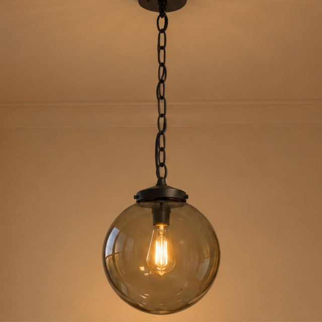 Bring sculptural simplicity to your room with this circa 1970s smoked-glass globe pendant, finished with black metal...
