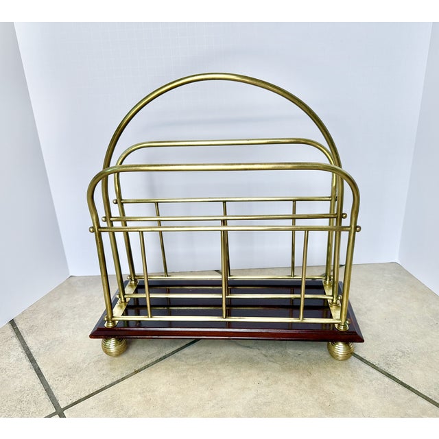 Antique English Victorian era newspaper and magazine rack featuring a brass frame on a dark wood base.