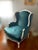 This antique French Provincial wingback chair showcases timeless traditional design with a beautifully carved warm, white...