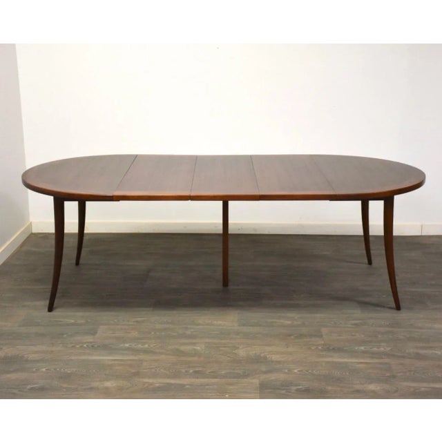 A mid century modern mahogany dining table designed by Harvey Probber with three 15.875” leaves and one 14.375” leaf which...