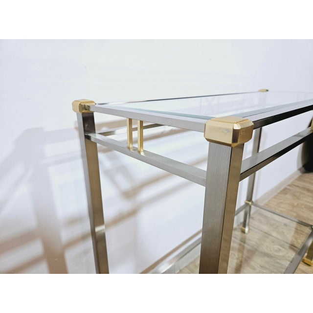 The designer console has a rectangular metal frame with a shiny chrome and gold finish for a luxurious feel. The tabletop...